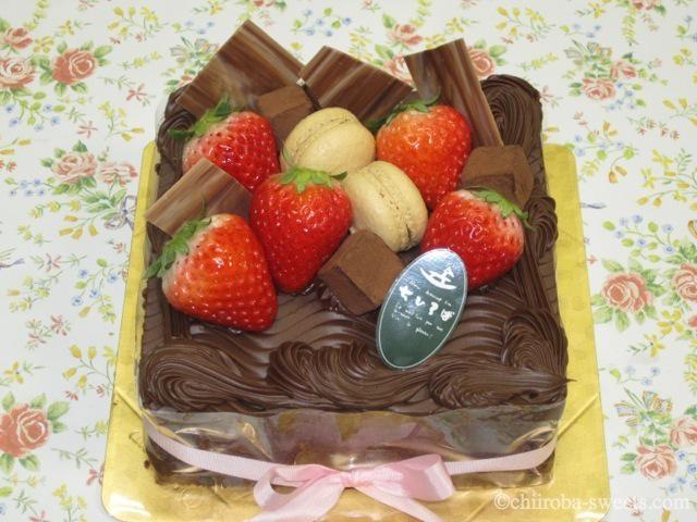 バースデイケーキ２ チョコの国から...デコレーション１５×１５センチ<br><br>ココアのスポンジに、ガナッシュチョコを贅沢にサンドしました。チョコ好きな方に...上に飾ったフルーツがお洒落なデコレーション。￥４０００（４３２０円）：しあわせ菓子工房 SaCHI